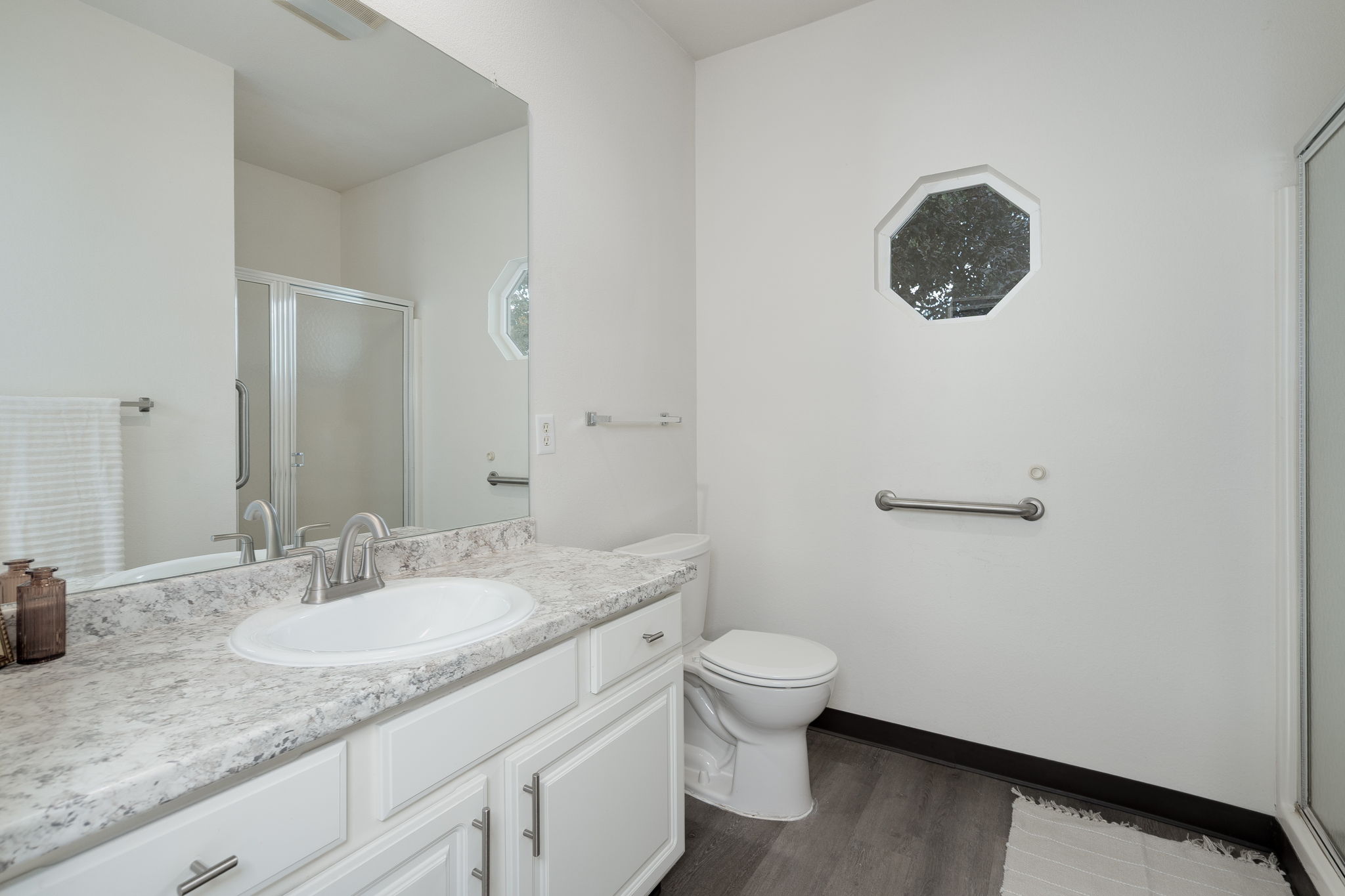 A bathroom with a white toilet, sink, and mirror.